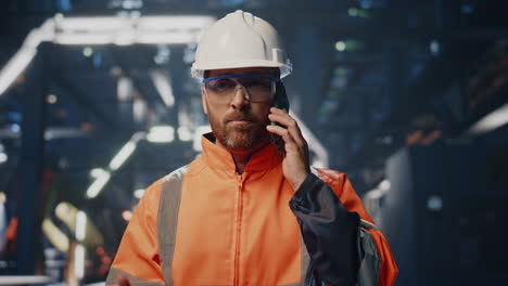 nervous industrial worker talking smartphone solving problems at factory closeup