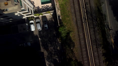 Estacionamiento-Al-Lado-Del-Ferrocarril,-Sol,-Sombras,-El-Dron-Despega.