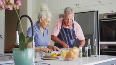 Kaukasisches-älteres-Paar-Mit-Schürzen,-Das-Gemeinsam-In-Der-Küche-Kocht