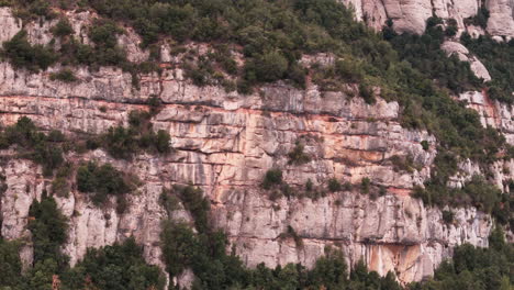 Drone-reveal-shot-of-epic-cliff-side-of-Montserrat-mountain-range-during-overcast-day