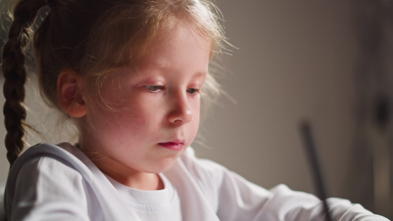 маленькая девочка рисует цветной лист за столом в классе.