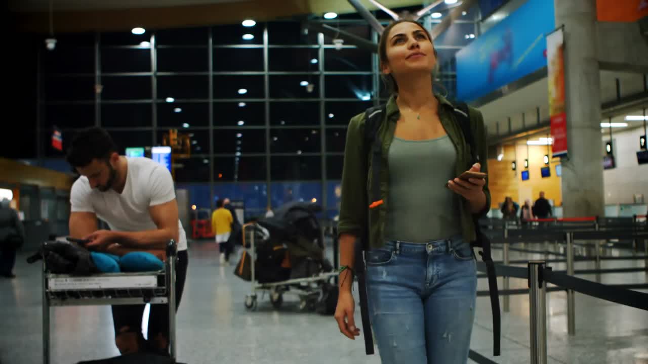 viajeros que utilizan el teléfono móvil y miran el tablero de salida 4k