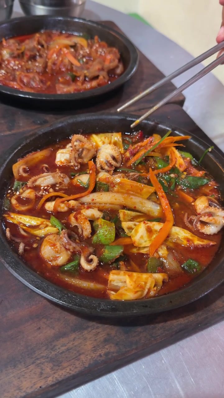Seseorang Menggunakan Sumpit untuk Makan Gurita Tumis Pedas