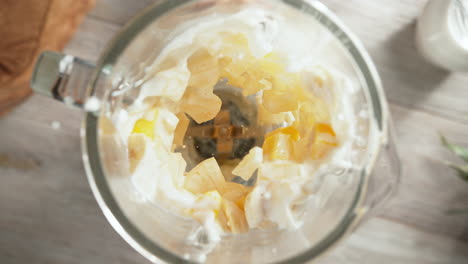 pineapple, mango, and banana smoothie mixed in a glass blender in slow motion, top view, inside of the device