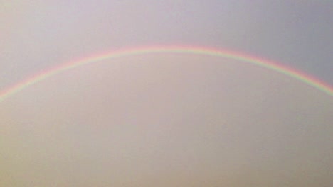 right to left wide panning shot of half circle double rainbow in the sky