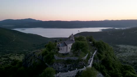 fly over church revealing beautiful lake at sunset, montenegro