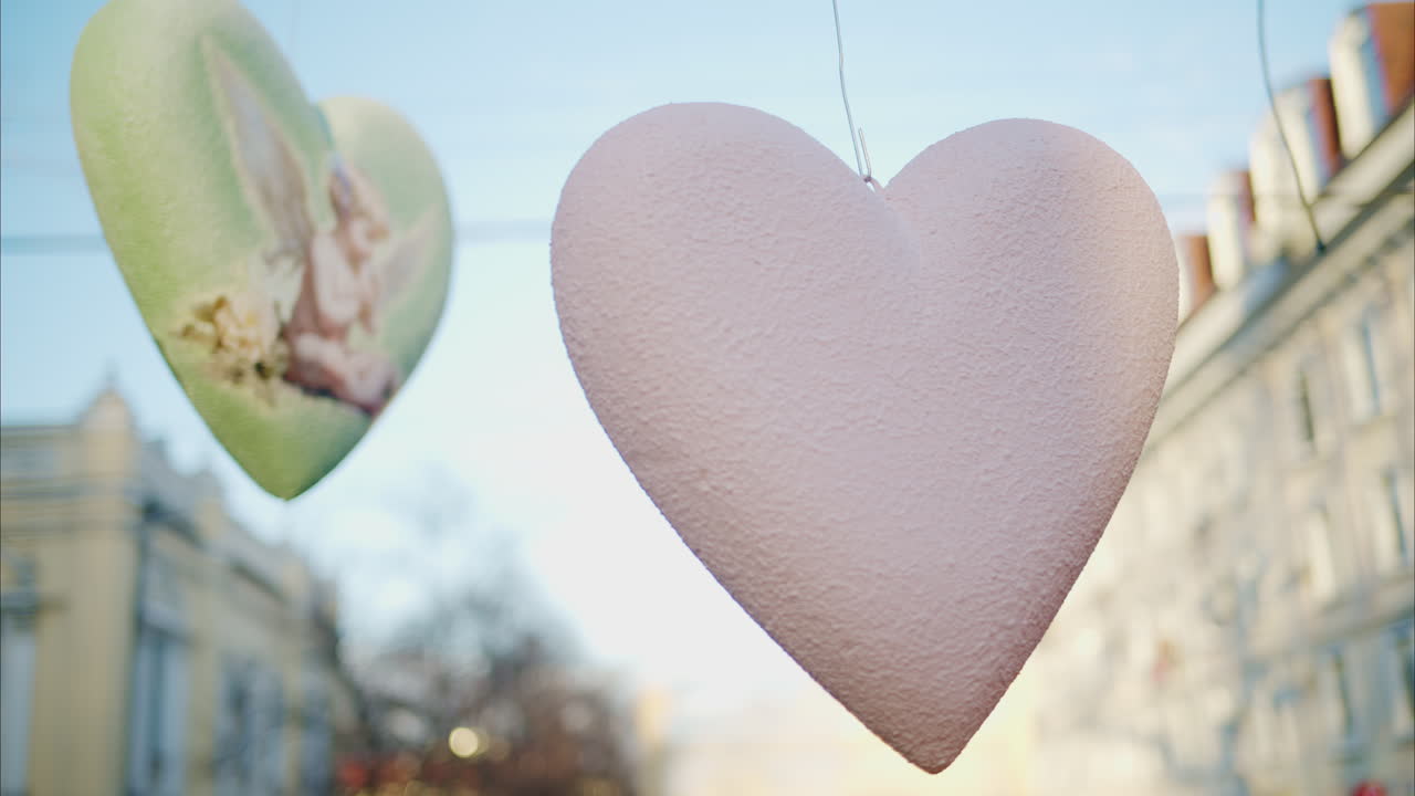 Hanging heart-shaped decorations moving in the wind, blurred city view