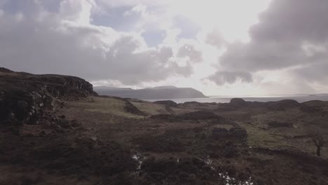 Aerial-shot-flying-south-towards-the-island-of-Mull,-from-the-island-of-Ulva,-slow-and-low-over-farmland-and-ruins-of-stone-built-crofts