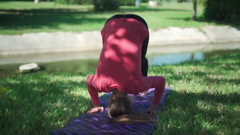 woman practicing supported headstand in park