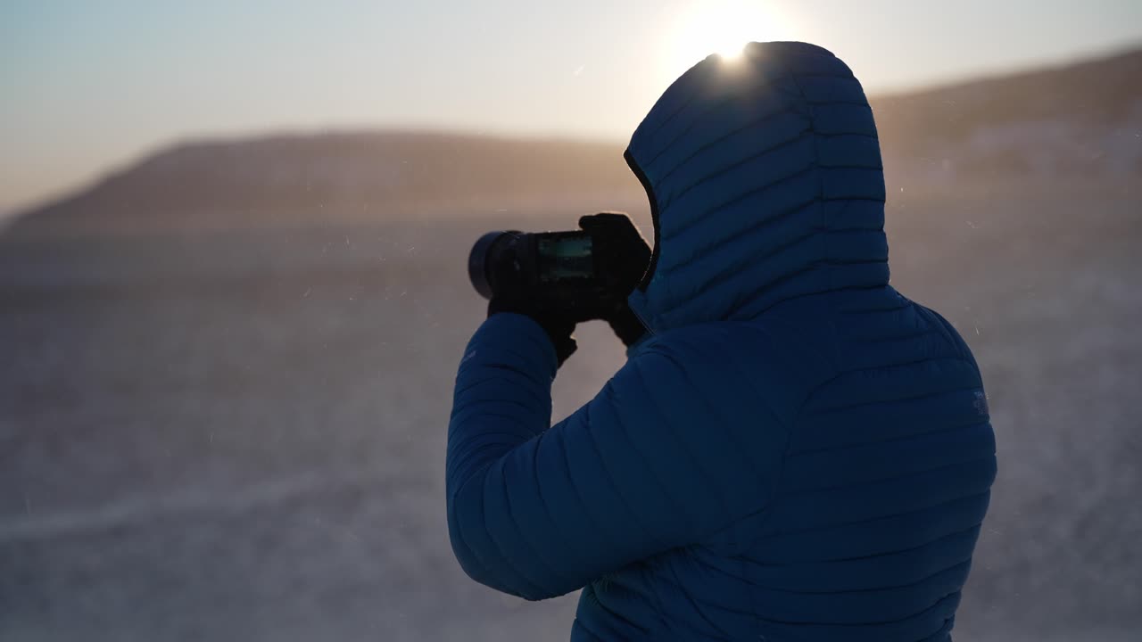Een warm ingepakte fotograaf die een foto maakt.