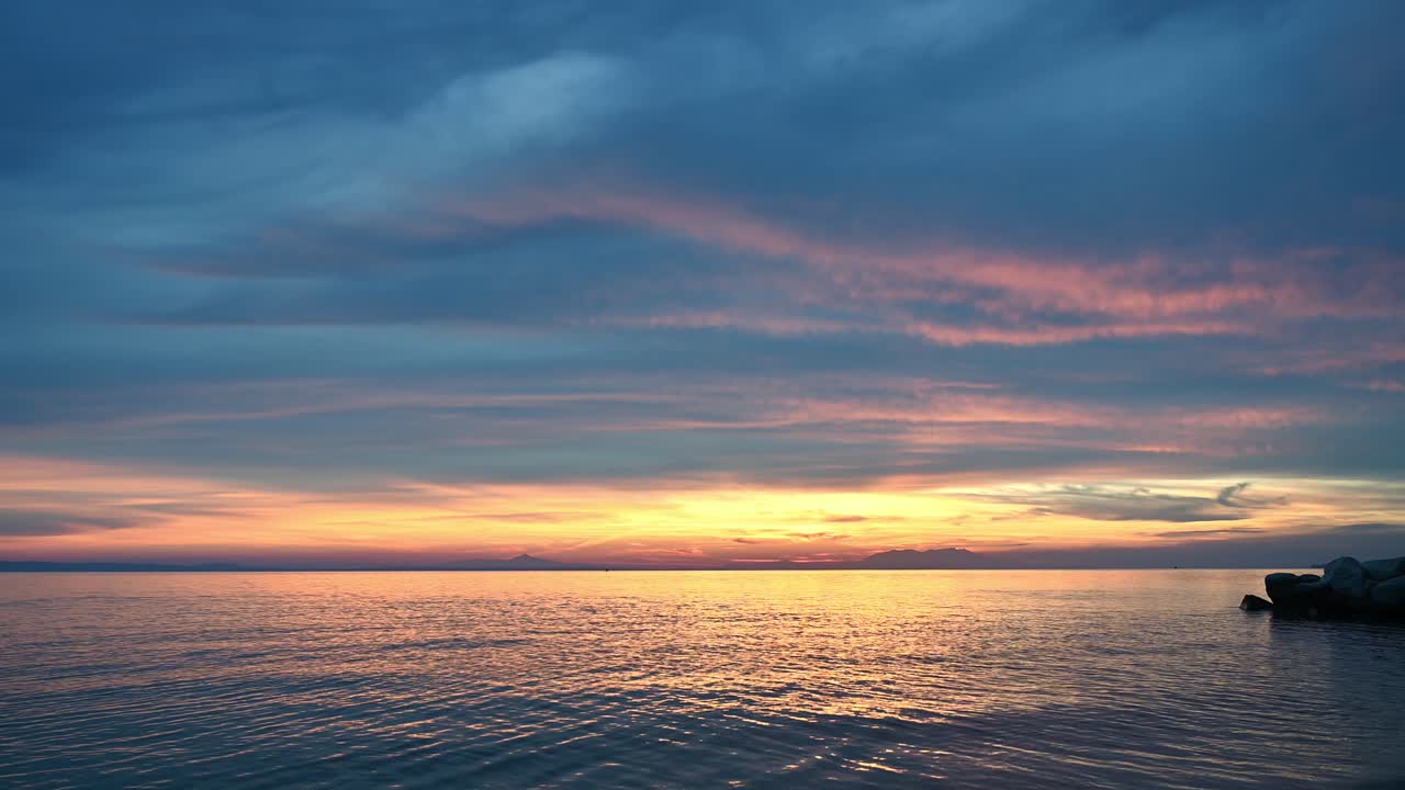 Tramonto sul Mar Egeo. Illuminazione gialla, terra in lontananza, acqua, Grecia