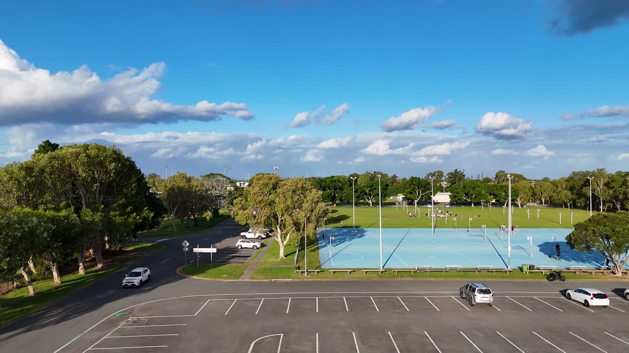 Drone footage captures empty netball courts and parking lot under clear skies at Gold Coast, Australia