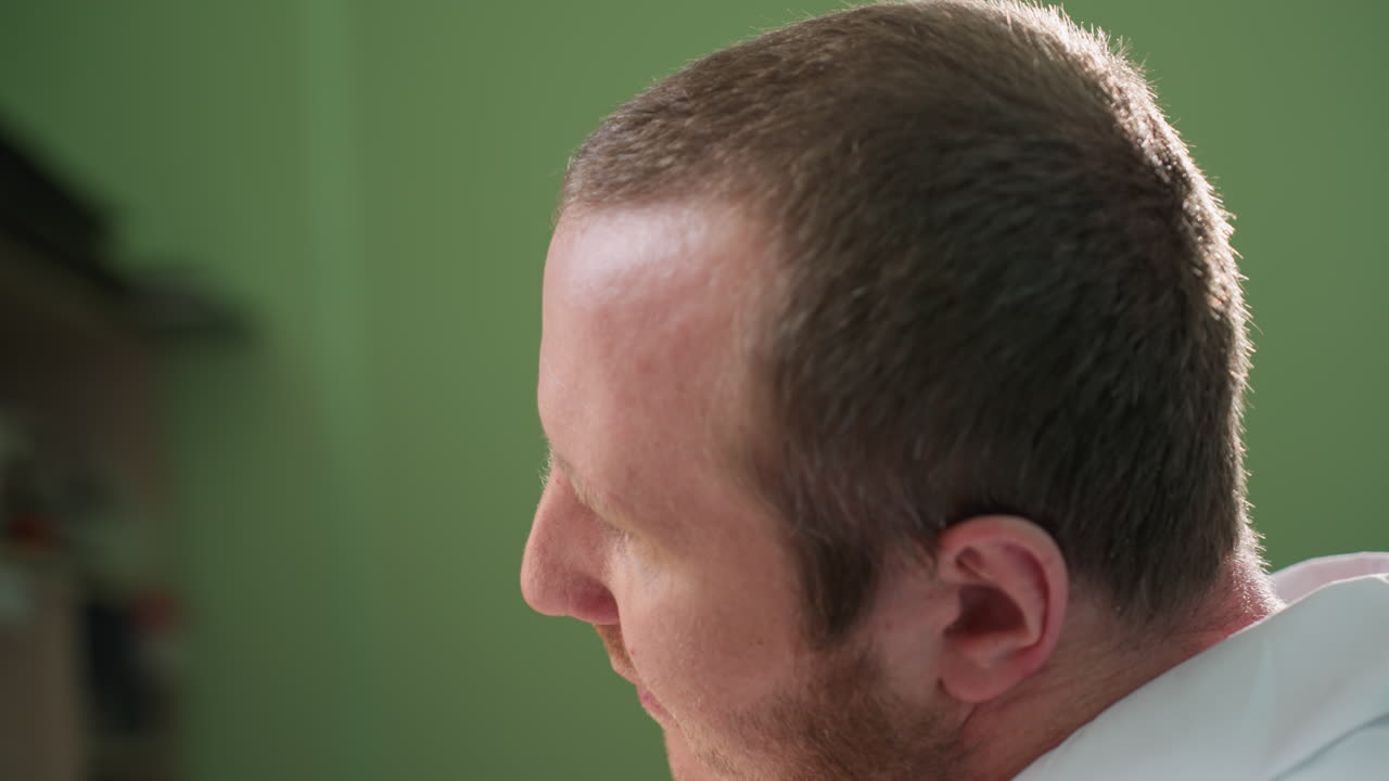 백색 실험실 코트를 입은 기술자가 현미경으로 쳐다보며 작업에 집중하는 근접한 모습