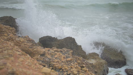 slow motion cinematic shot of a wave crashing on rocks