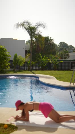 mujer haciendo ejercicio de tabla junto a la piscina