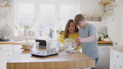 una pareja de jóvenes con síndrome de down se divierten horneando en la cocina en casa.