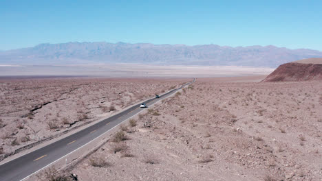 Coche-Blanco-Conduciendo-Por-Una-Carretera-Asfaltada-A-Través-De-Las-Arenas-Del-Desierto