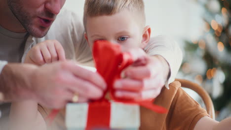 dad and boy wrap presents together