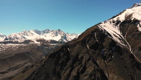 Tiro-Aéreo-Cerrando-En-El-Pico-De-La-Montaña-Con-La-Cordillera-De-Los-Andes-En-El-Fondo-En-Un-Día-Claro-Y-Crujiente-4k