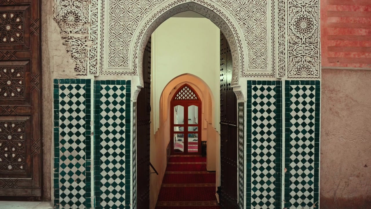 Person Riding Scooter Past Ornate Moroccan Archway
