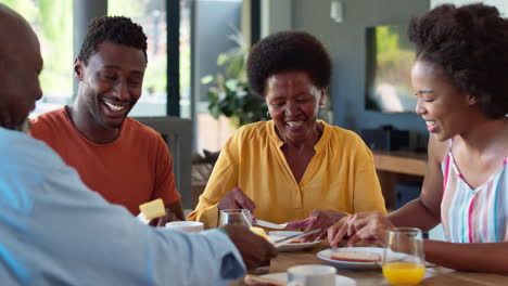 Family-Shot-With-Senior-Parents-And-Adult-Offspring-At-Breakfast-Around-Table-At-Home