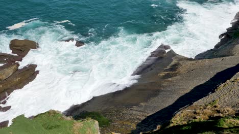 olas del océano lavando grandes rocas en la costa de colinas rocosas