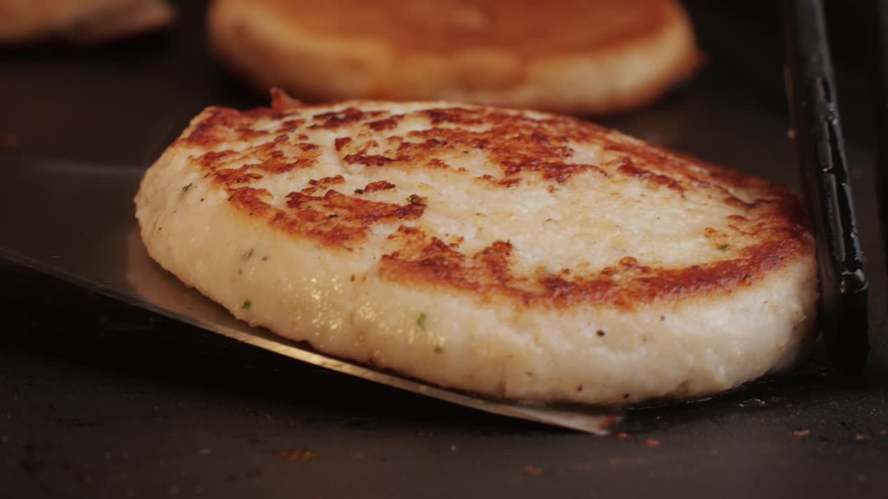 Cooking American fat smash burger on grill close-up. Chiken or fish cutlet smashing by burger press. The chef in kitchen of the restaurant making cutlets for burgers - smash burger beefsteak. Fast and street food concept. High quality 4k footage
