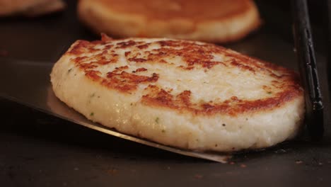 Cooking American fat smash burger on grill close-up. Chiken or fish cutlet smashing by burger press. The chef in kitchen of the restaurant making cutlets for burgers - smash burger beefsteak. Fast and street food concept. High quality 4k footage