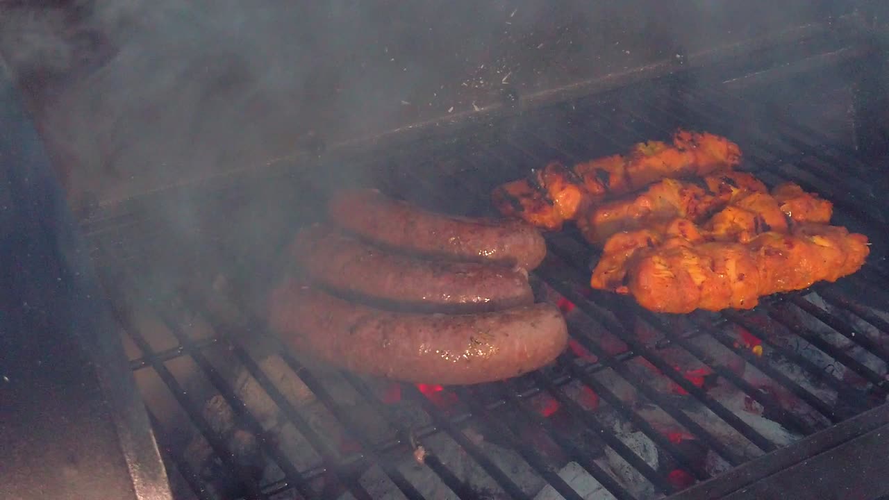 mirando las salchichas y el pollo sate recibiendo el calor y el humo de la barbacoa