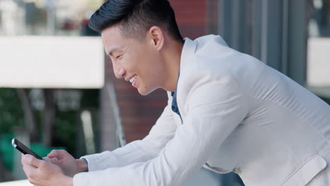 Asian-man,-texting-and-phone-in-office-with-smile