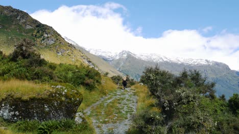 tiro largo da pessoa que caminha no caminho rural da montanha no parque nacional de aspiração do monte durante o verão - cordilheira nevada no fundo