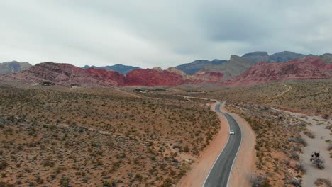 aerial drone shot of a desert road with scenic mountains in the background