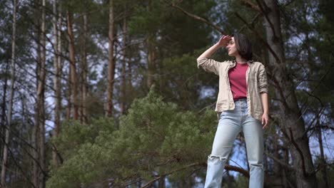 a pretty brunette girl looks out over the horizon in the forest.