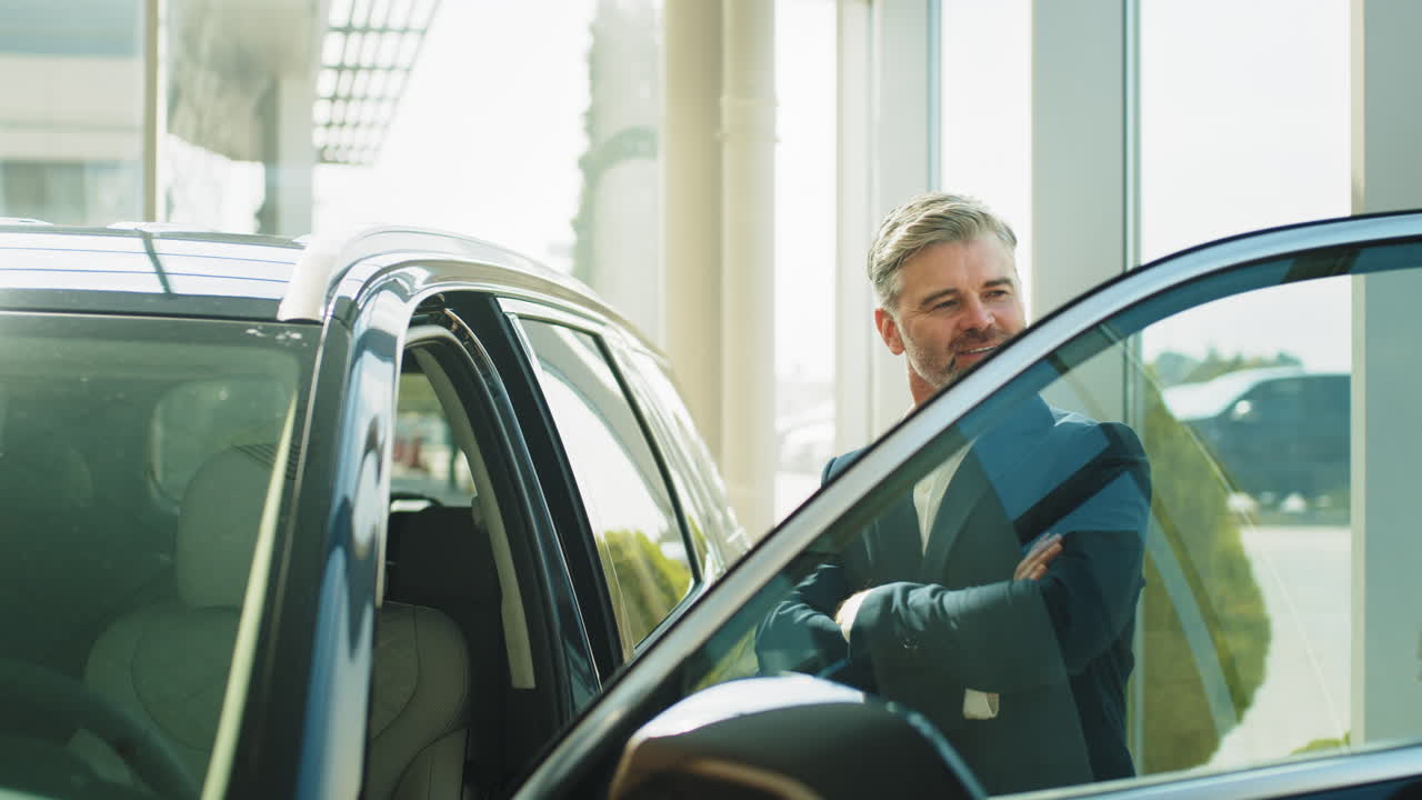 Man in a suit examining a car at a dealership