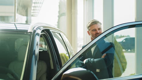 hombre en un traje examinando un coche en un concesionario