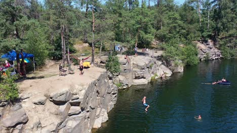 Aerial-drone-video-of-people-cliff-jumping-in-a-lake-and-swimming-on-a-summer-day-in-Kyiv-Ukraine