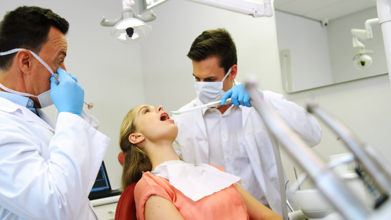 dentistas examinando a un paciente masculino con herramientas