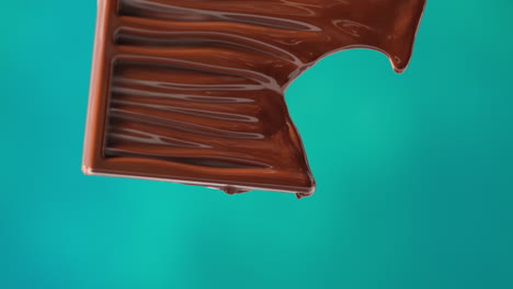 close up of melting chocolate bar against blue coloured background with copy space 1