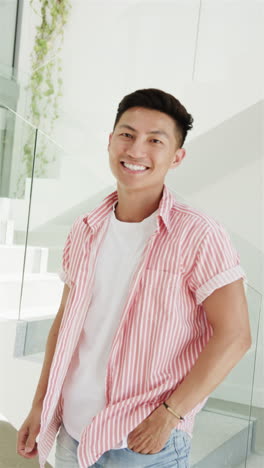 vertical video: asian male with bright smile standing on stairs