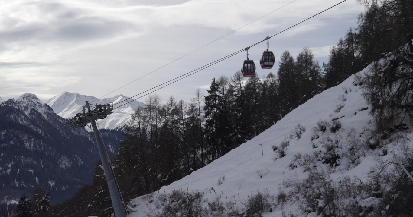 Cinematic alpine cable car gliding above snowy mountain slopes under soft winter sun, with dramatic peaks and vast landscape creating a serene, luxury atmosphere for travel and storytelling.