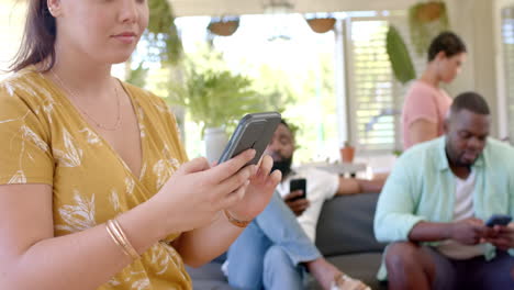 using smartphones, group of diverse friends relaxing together in living room