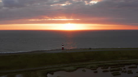 the lighthouse of westkapelle during a bright orange sunset, with a lot of wind