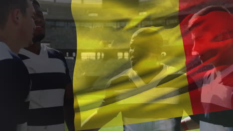 animation of belgium flag waving over diverse male players discussing before match at stadium