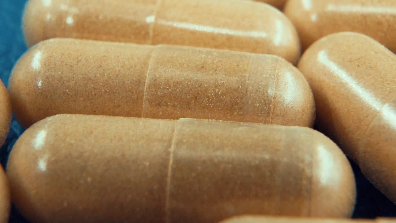 una macro en cámara lenta tomada en un laboratorio de una cápsula médica en movimiento con polvo, píldoras orgánicas, luz de estudio, 120 fps, full hd