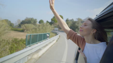 young woman sitting in car and raising hands