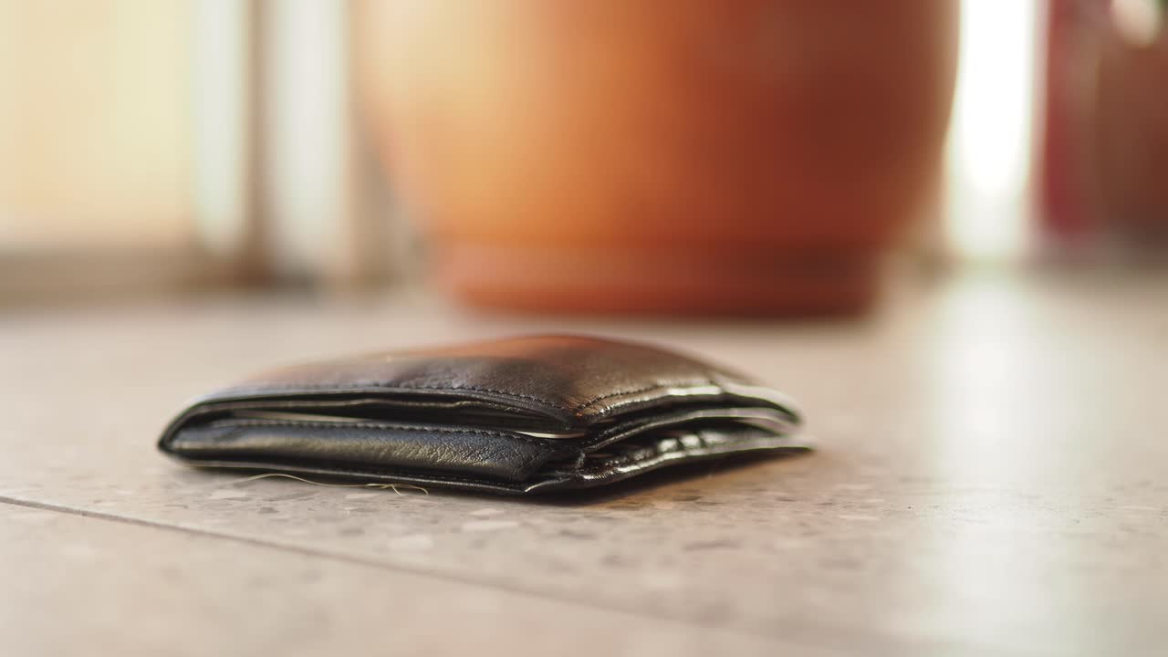 A black wallet lying on a tiled floor