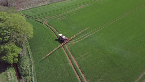 aerial view of a farmer sprayting crops in a field in aberdeenshire on a sunny day, scotland