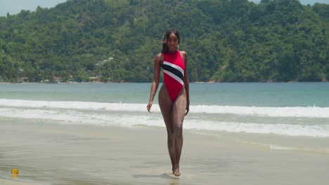 on the tropical island of trinidad, a young girl from trinidad in a bikini walking in the sand on the beach