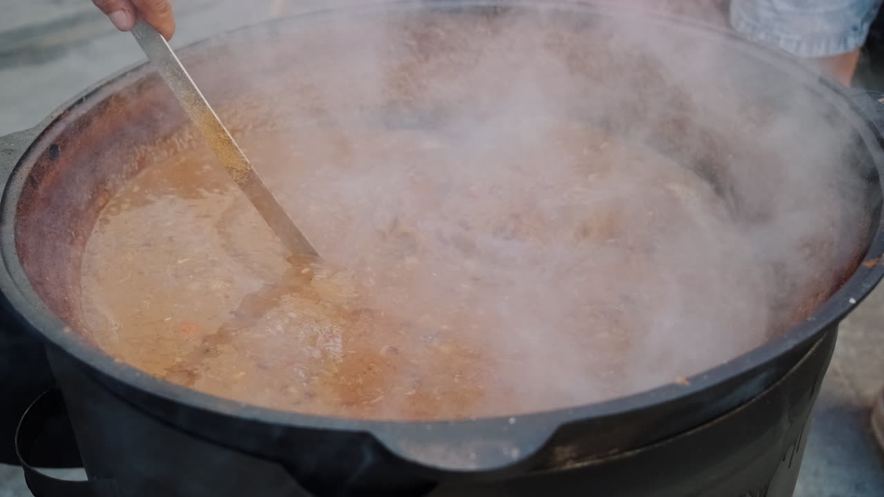 una gran olla de estofado cocinando al aire libre