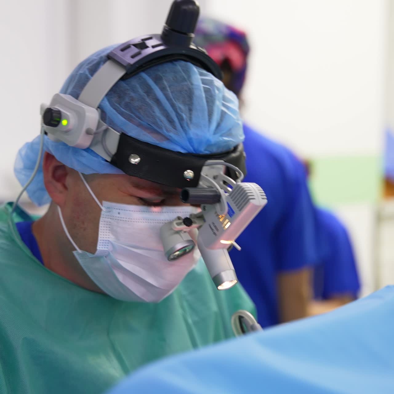 Surgeon with device glasses on his head sits near the patient talking. Portrait of a cheerful doctor doing his work